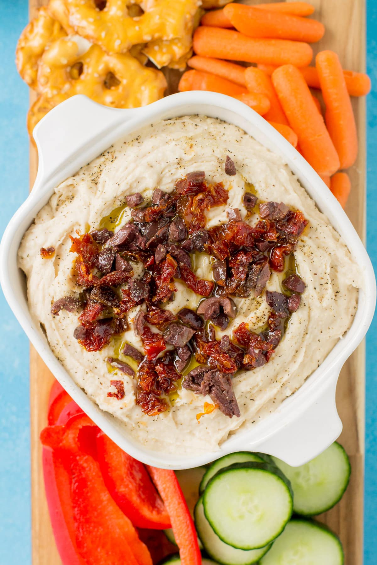 White Bean Hummus in a small white bowl on a cutting board with veggies and chips