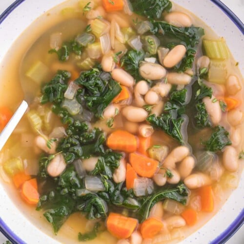 A bowl of Tuscan white bean soup on a white counter.