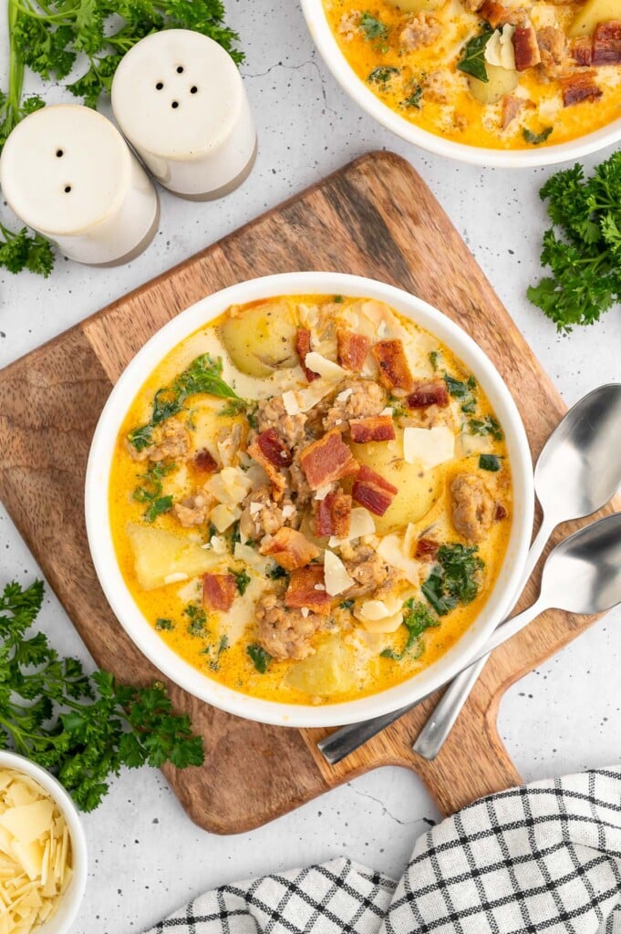 Healthy Zuppa Toscana Soup in a white bowl on a wooden cutting board on a white counter