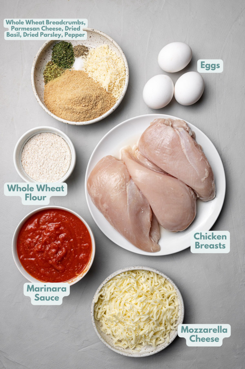 Ingredients for Easy chicken parmesan in white bowls: Chicken Breasts, mozzarella, marinara sauce, whole wheat flour, eggs