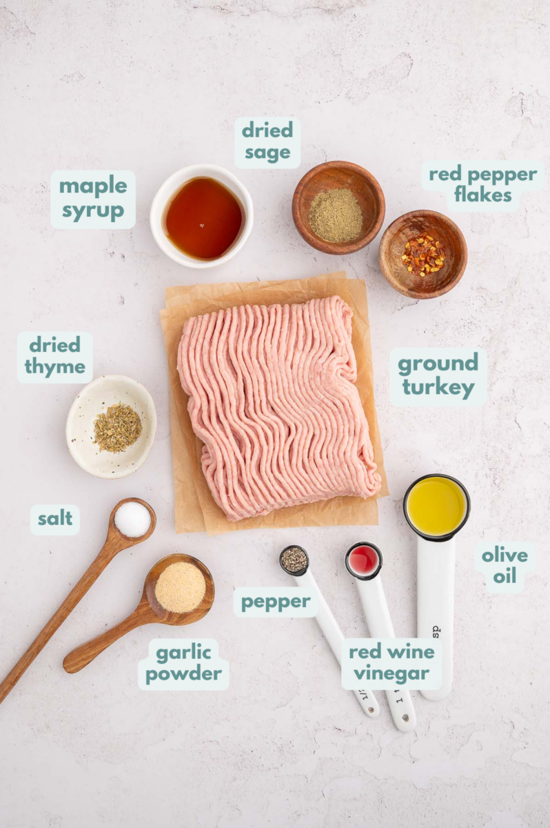 Ingredients for Turkey Breakfast Sausage in small bowls: ground turkey, maple syrup, red wine vinegar, spices