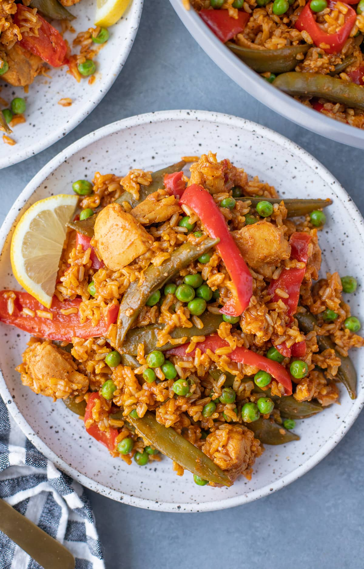 An overhead shot of High Protein chicken paella on a white plate on a grey background