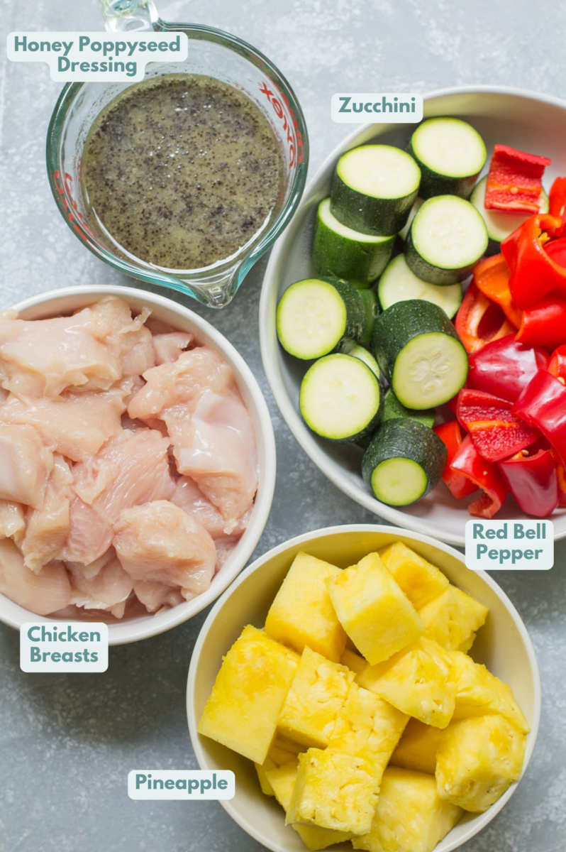 Ingredients for pineapple chicken kabobs laid out in white bowls on a grey background