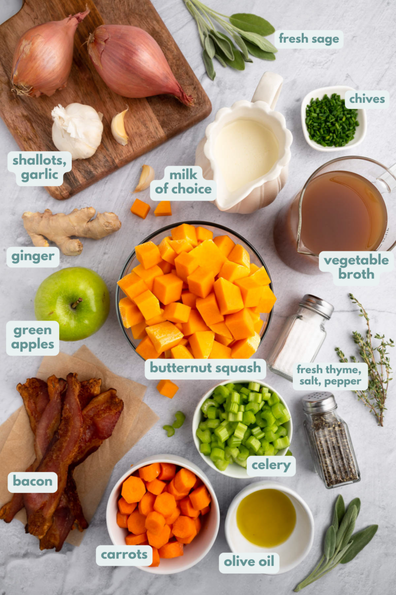 Ingredients for roasted butternut squash soup in small bowls: olive oil, butternut squash, celery, carrots, apple, shallot, garlic, thyme, sage, ginger, salt and pepper, vegetable broth, milk of choice