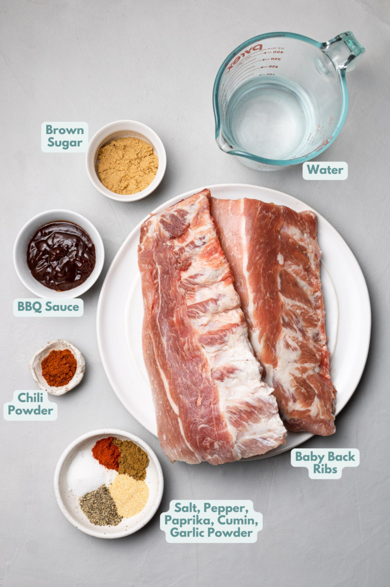 Ingredients for crockpot baby back ribs in white bowls: baby back ribs, brown sugar, water, apple juice, broth), bbq sauce, paprika, garlic powder, cumin, chili powder, salt, pepper