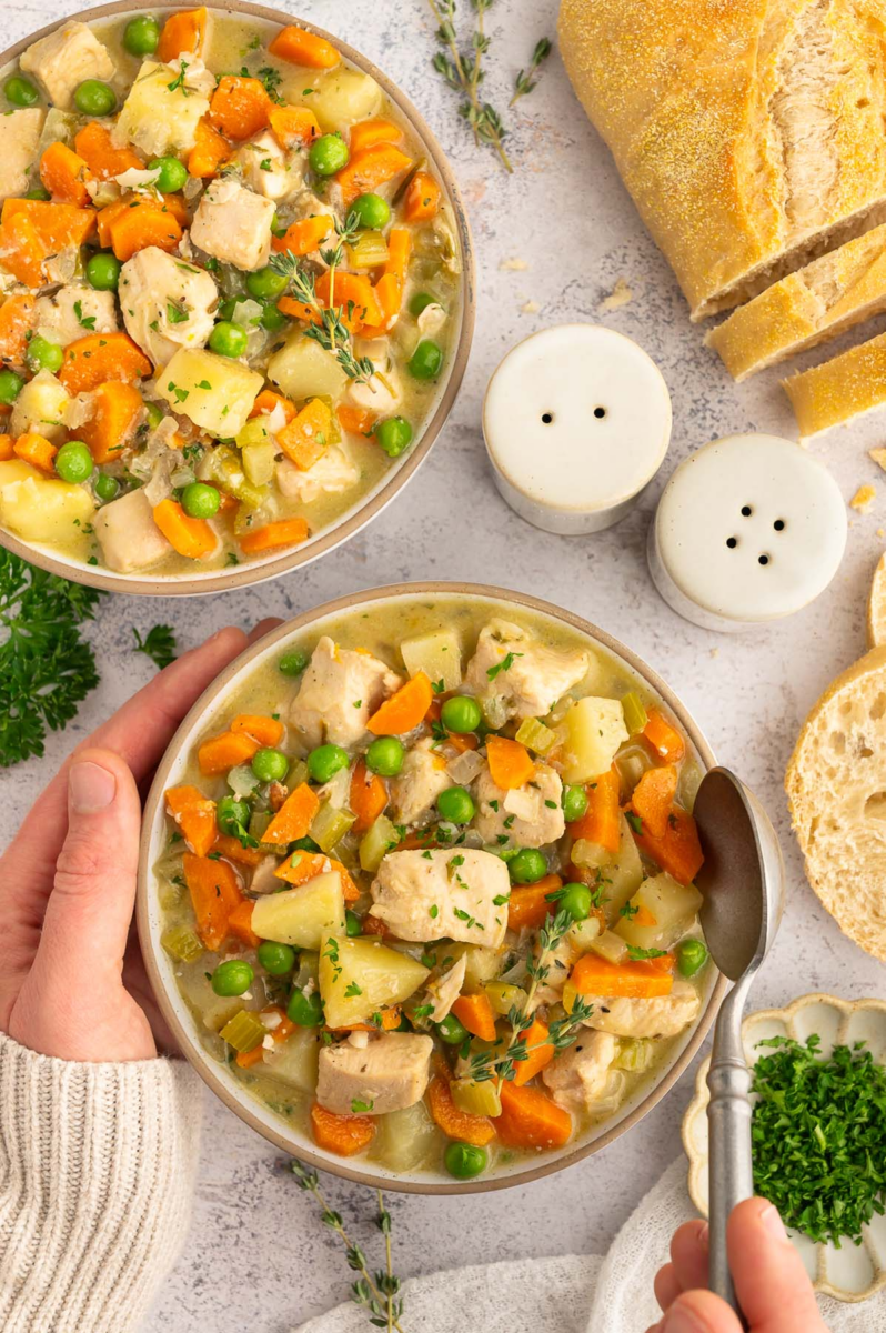 a big bowl of high protein chicken stew with a hand taking a spoonful out