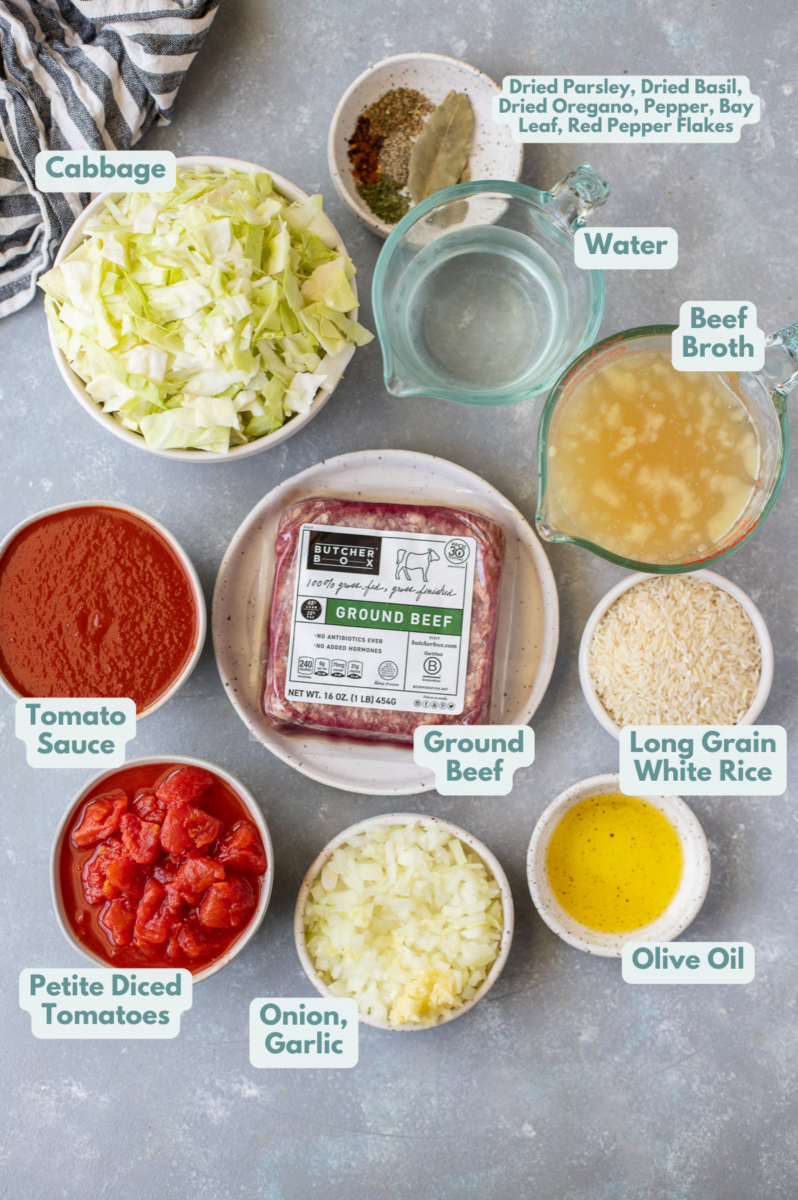 Ingredients for hamburger cabbage soup in small bowls: olive oil, ground beef, onion, garlic, cabbage, petite diced tomatoes, tomato sauce, water, beef broth, long grain white rice, spices